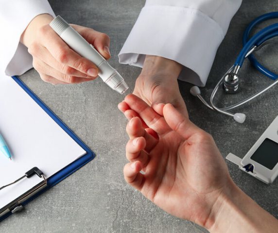 doctor-checking-blood-sugar-level-in-patient-diabetes-on-gray-table-850x580